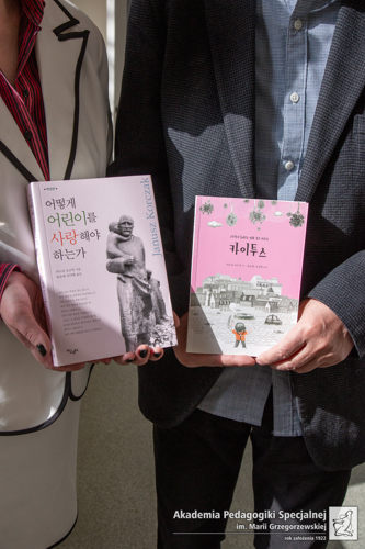 zbliżenie na ręce dwóch osób trzymające dwie książki Korczaka, wydanie koreańskie.jpg